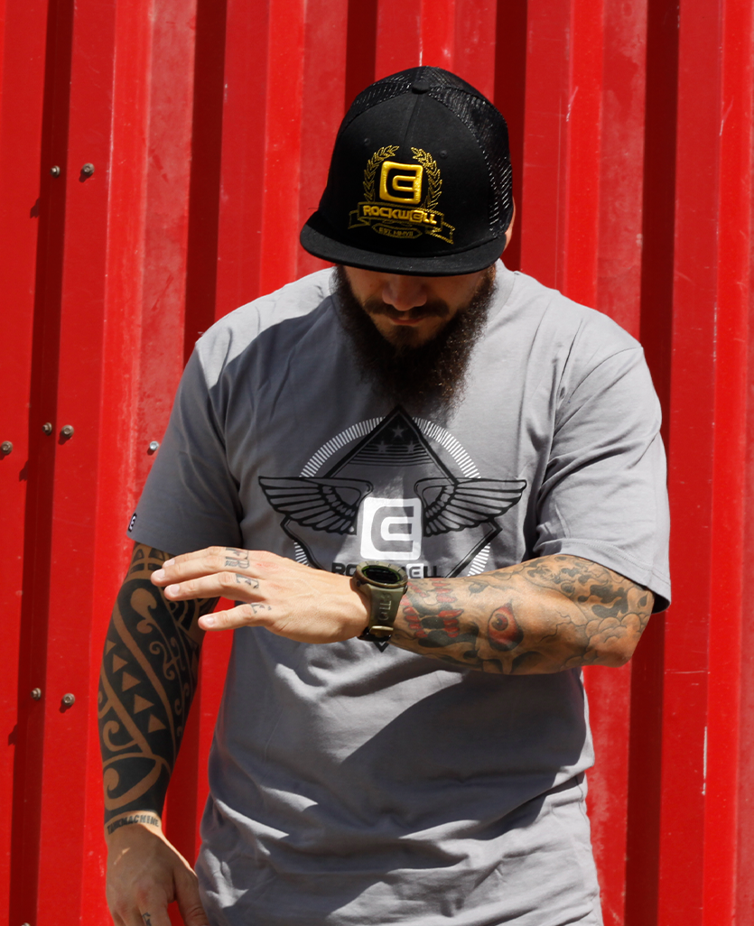 man looking at his coliseum watch while wearing rockwell black/gold roman mesh back hat