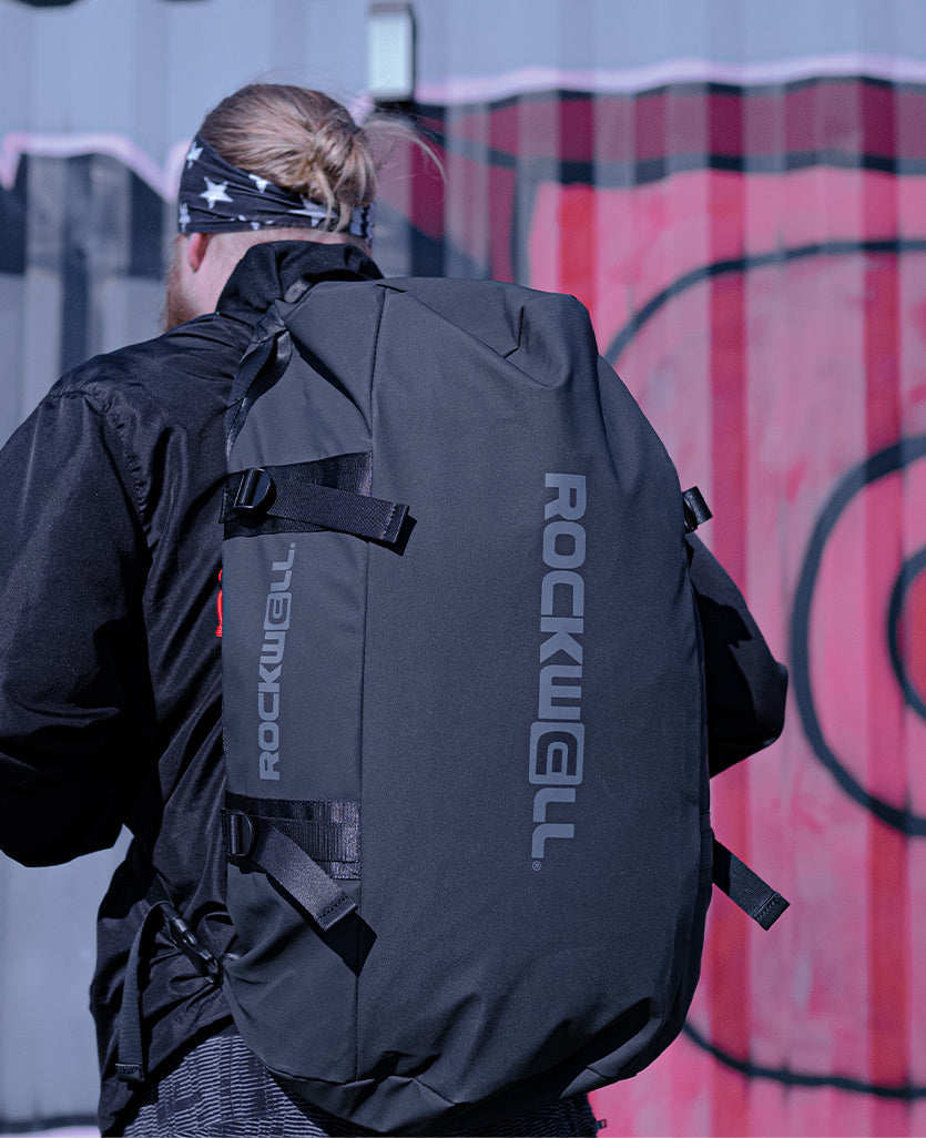 back of man wearing Shogun - 54 Liter Deluxe/Water Resistant Duffle Bag (Black)